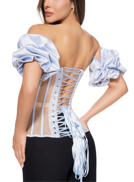 Woman wearing a light blue off-shoulder top with a lace-up back 